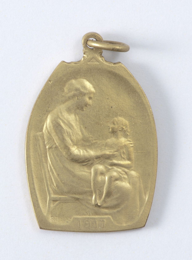 Goldmedaille mit Relief einer Frau in weißer Kleidung mit einem Knoten im Haar, die ein Kind hält, beide schauen sich zärtlich an, beschriftet mit "Mutter und Kind."