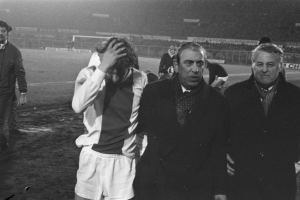 Schwarzes und weißes Bild einer Gruppe von Männern, die auf einem Fußballfeld stehen und nach einem Sieg bedrückt aussehen.