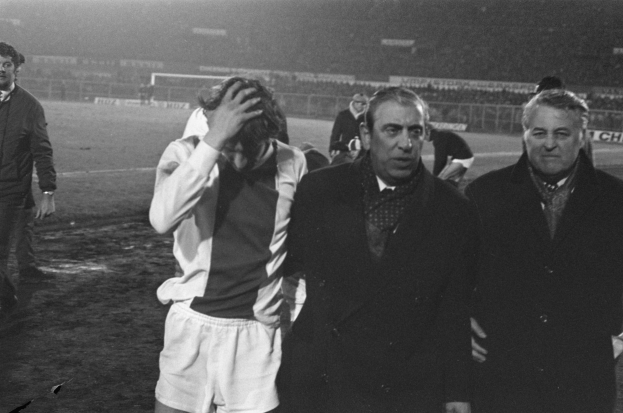 Schwarzes und weißes Bild einer Gruppe von Männern, die auf einem Fußballfeld stehen und nach einem Sieg bedrückt aussehen.