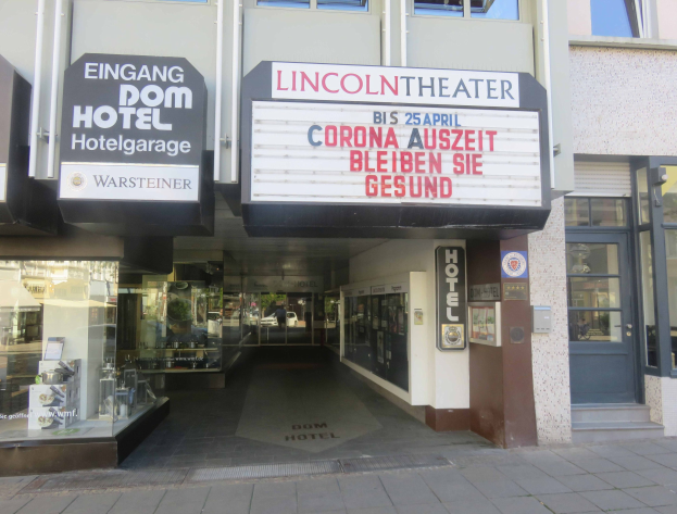 Außenansicht des Lincoln Theaters in Berlin, Deutschland, mit Glasfenstern und -türen sowie einer Tafel mit Text und einem belebten Innenraum