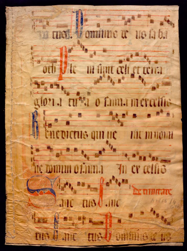 Ein illuminiertes Manuskript mit Musiknotation auf einem Blatt Papier vor einem dunklen Hintergrund, gefüllt mit Text und musikalischen Symbolen, die ein komplexes Design bilden.