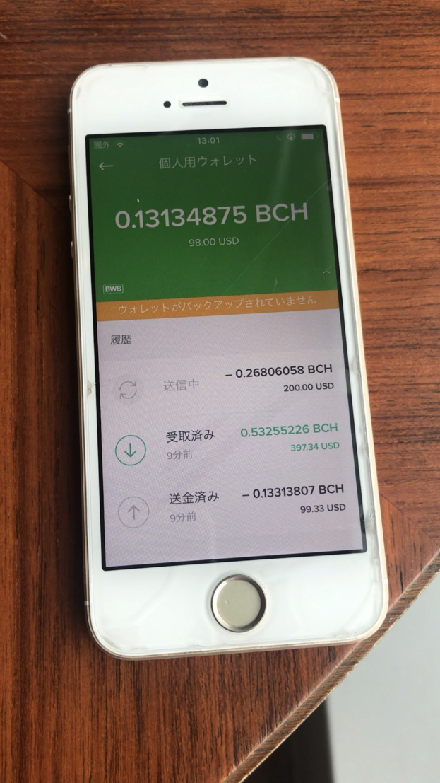 Weißer iPhone auf einem hölzernen Tisch, der den Text "Wie man online Geld verdienen kann" und Gewinnzahlen auf dem Bildschirm anzeigt.