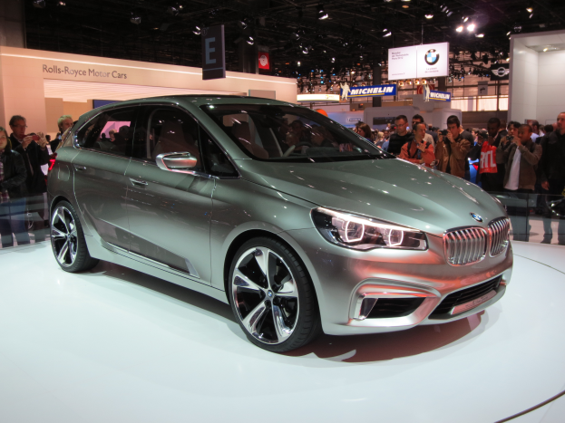 Ein BMW 2er Active Tourer Concept Wagen wird auf der IAA in Frankfurt präsentiert, umgeben von Menschen mit Kameras und beleuchteten Schildern im Hintergrund.