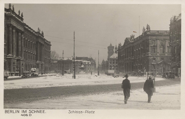 Zwei Menschen, die eine verschneite Straße in Berlin, Deutschland, entlanggehen, mit Gebäuden, Pfählen und Fahrzeugen, die den Weg säumen, unter einem sichtbaren Himmel.