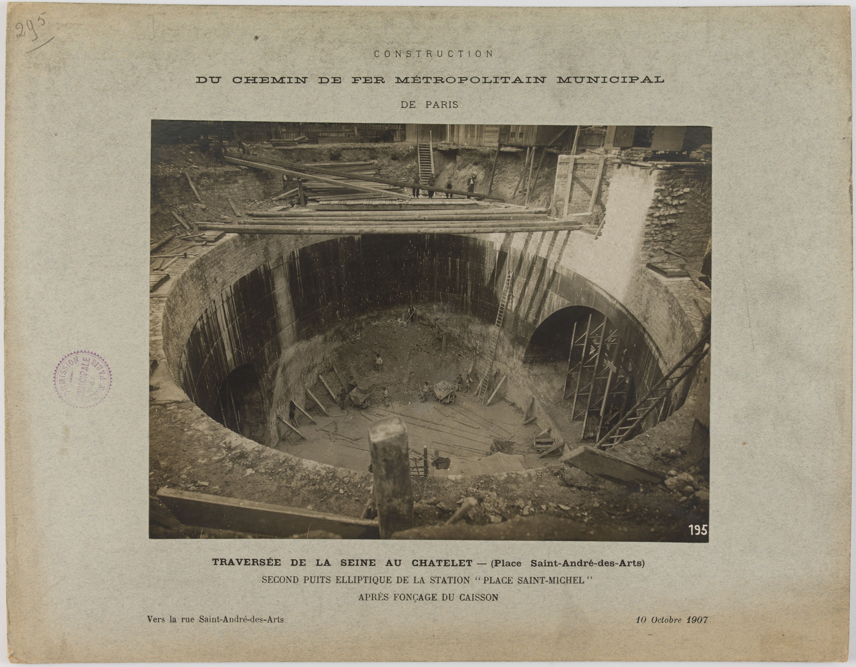 Schwarzes und weißes Foto eines Tunnels im Bau mit einem Stempel auf der linken Seite und Text unten.