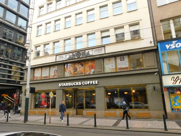 Ein Starbucks-Kaffeeladen an einer Straßenecke in Berlin, Deutschland, mit Passanten, einem Auto, Strommasten und Schildern am Gebäude.