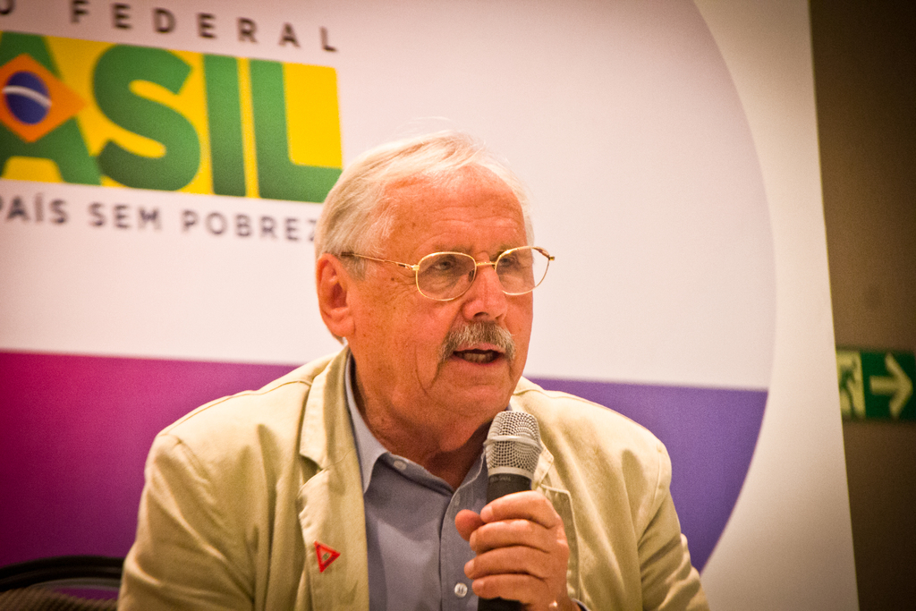 Eine Person spricht in ein Mikrofon mit einem Banner mit der Aufschrift 'Bundes' dahinter.