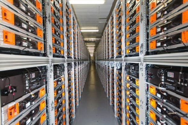 Eine lange Reihe von Servern in einem Rechenzentrum mit elektronischen Geräten in den Racks und Anzeigelampen oben.