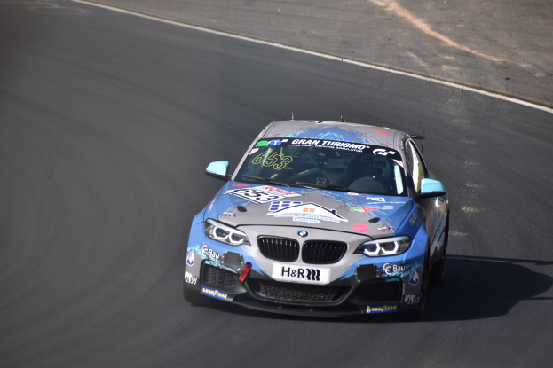 BMW M2 GT3-Rennwagen fährt auf einer Rennstrecke mit Text und Zahlen auf der Karosserie.