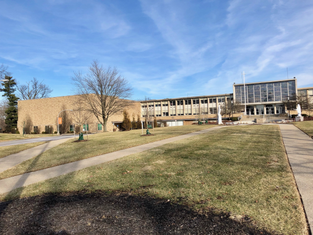 Großes modernes Schulgebäude an der University of Illinois at Chicago mit einem Weg vor dem Gebäude, umgeben von Gras, Bäumen und Laternen unter einem bewölkten Himmel.