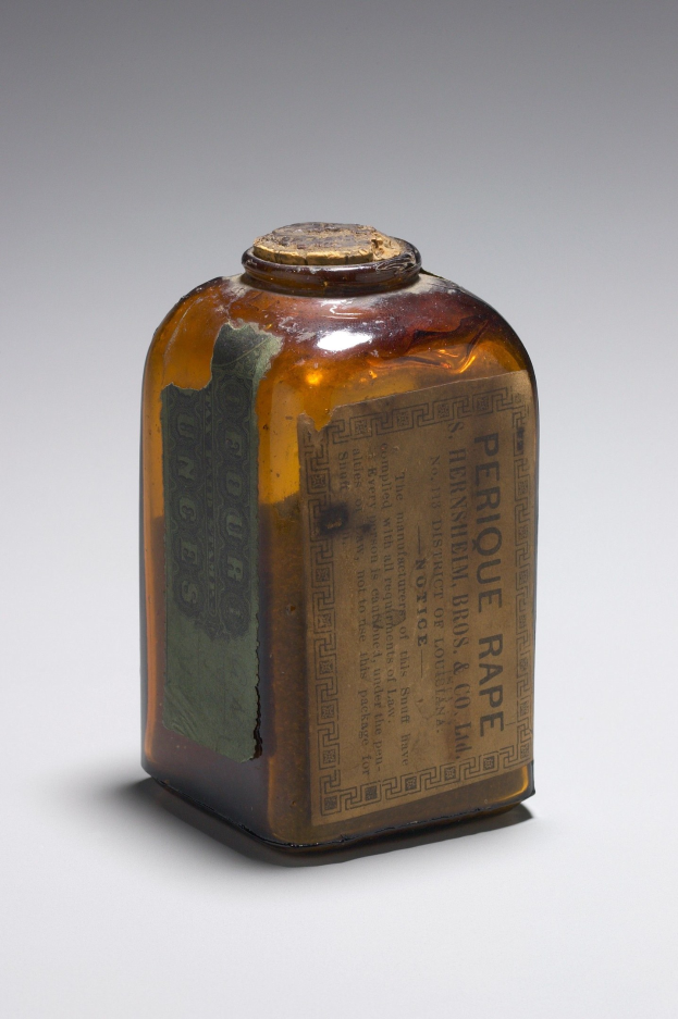 Eine braune Glasflasche mit der Aufschrift "Perique Rape" steht auf einer weißen Oberfläche.