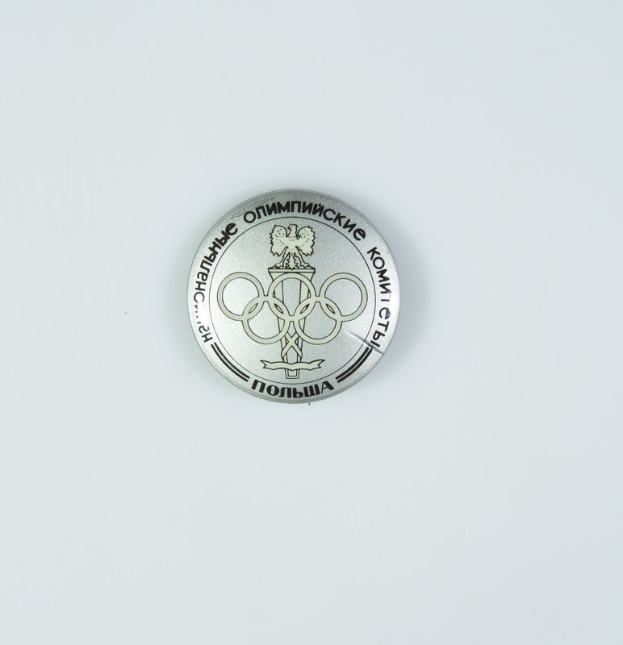 Eine runde Silbermedaille mit dem Olympischen Logo und Text, vor einem weißen Hintergrund.