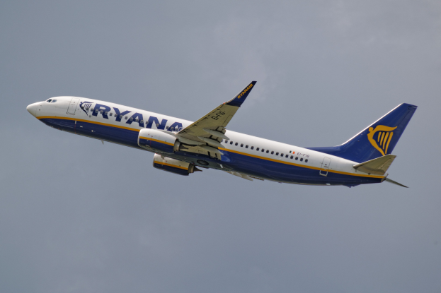 Ein Ryanair Boeing 737-800 mit weiß-blau-gelben Lackierung fliegt gegen einen blauen Himmel.