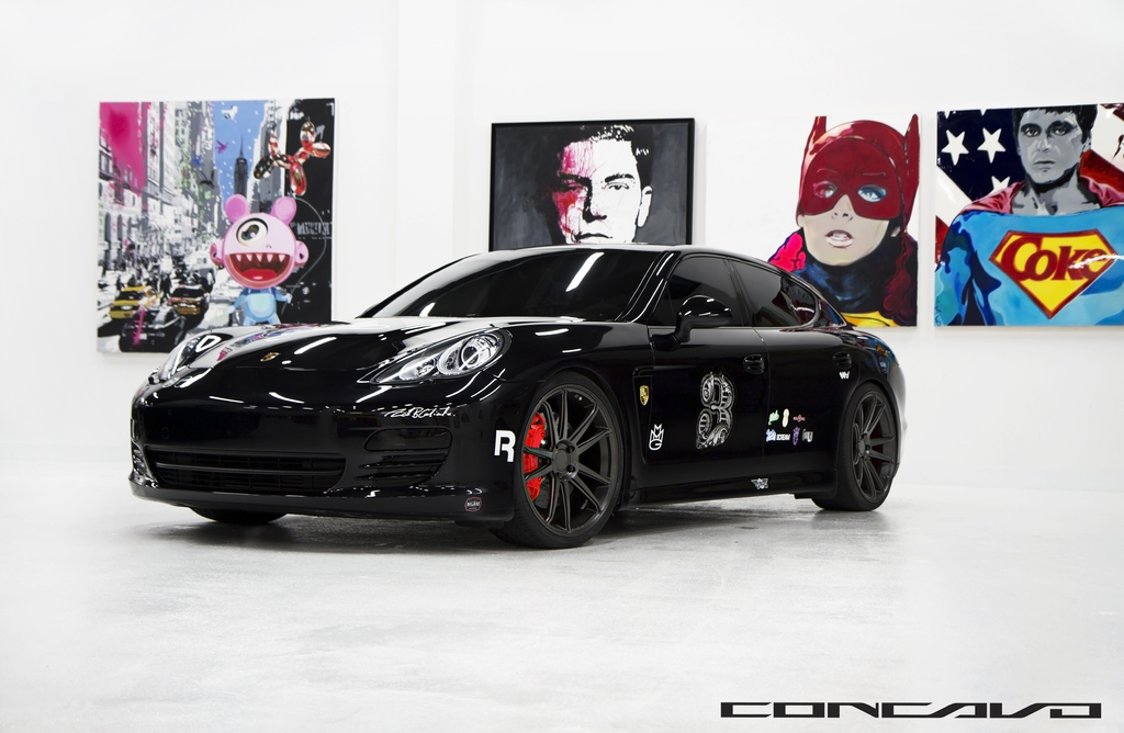 Ein schwarzer Nissan-Sportwagen mit Cartoon-Postern im Hintergrund und einem kleinen Zitat unten.