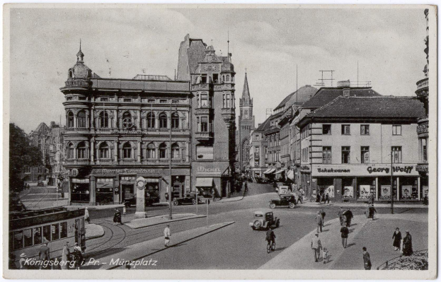 Schwarz-weißes Foto einer belebten Münchner Stadtstraße mit Fußgängern, Fahrzeugen und Gebäuden, Bäumen im Hintergrund und Text am unteren Rand.