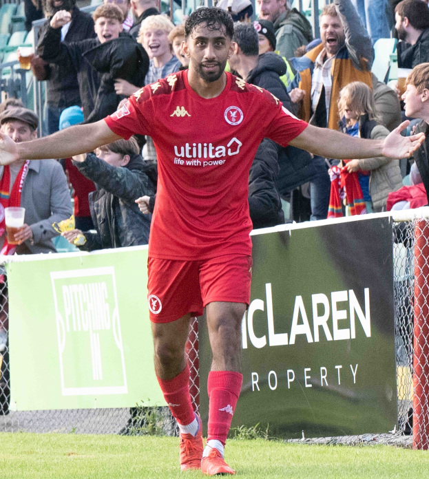 Ein Fußballspieler in roter Uniform rennt mit ausgebreiteten Armen auf einem Feld, umgeben von Zuschauern, mit einem "Middlesbrough FC v Swansea City - Sky Bet Championship"-Schild im Hintergrund.