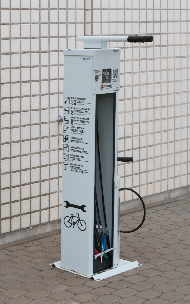 Eine Ladestation für Elektrofahrzeuge an der Seite eines Gebäudes mit einer Maschine auf dem Boden und einer Wand im Hintergrund.