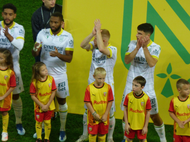 Eine Gruppe von Fußballspielern in Uniformen klatscht auf einem Ligue-1-Feld