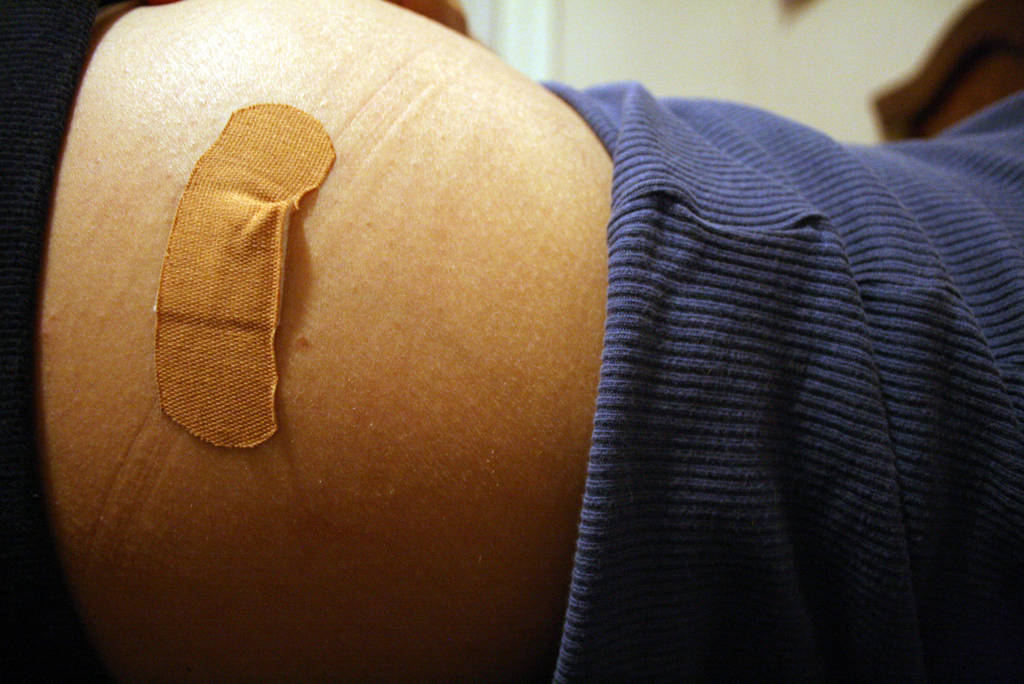 Ein Nahaufnahme eines Verbandpflasters auf der Haut einer Person mit einem unscharfen Hintergrund.