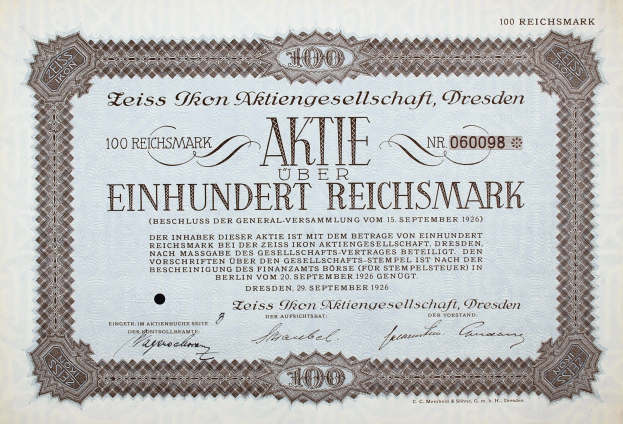 Ein altes deutsches Aktienzertifikat mit schwarzem Rand, auf dem der Text 'Aktie über Einhundert Reichmark' steht, was auf Englisch '100 Reichmarks' bedeutet.