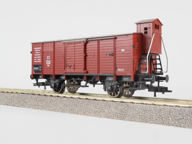 Roter Gepäckwaggon auf Schienen mit weißem Hintergrund und Text an der Seite.