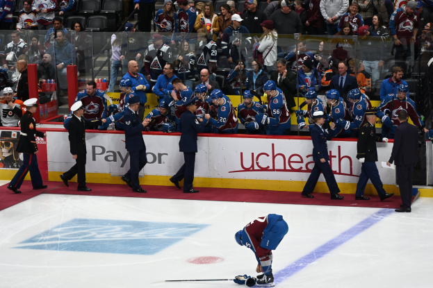 Eishockeyspieler auf dem Eis umgeben von Mannschaftskameraden und Gegnern, mit Zuschauern im Hintergrund bei einem NHL-Spiel zwischen Colorado Avalanche und San Jose Sharks am 24. März 2015.