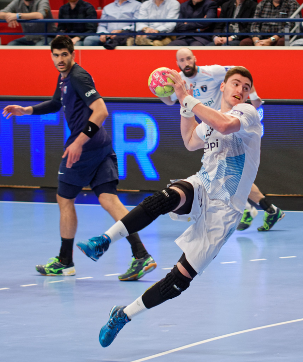 Eine Gruppe von Männern spielt Handball auf einem Court während des Futsal-Weltmeisterschaft 2019, mit Zuschauern im Hintergrund und einer Anzeigetafel, die die Veranstaltungstage anzeigt.
